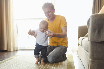 Father assisting son in walking at home