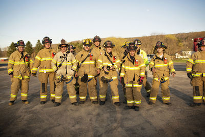 Portrait of firefighters standing on field