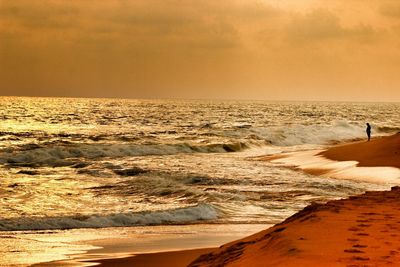 Waves reaching at beach during sunset