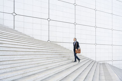 Mature businessman with bag moving up on steps