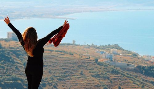 Rear view of woman standing on landscape against sky