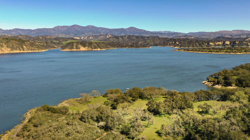 Scenic view of sea and mountains against clear blue sky