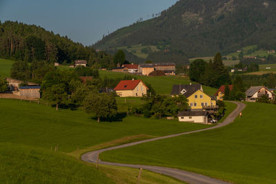 Houses on field by buildings against mountains