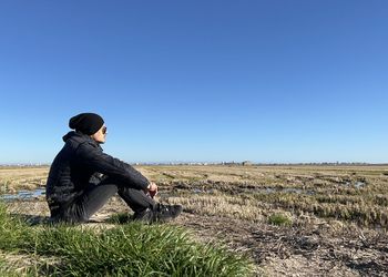 Side view of man standing on field against clear blue sky