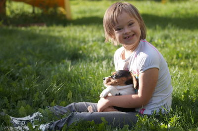 Portrait of smiling girl with dog sitting on grass