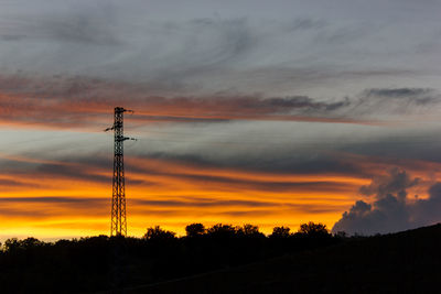 Low angle view of silhouette electricity pylon against sky during sunset