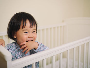 Close-up of smiling girl in crib at home