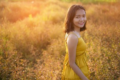 Portrait of a smiling young woman standing on field