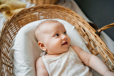 Baby lies in a wicker basket gray background willow eco style