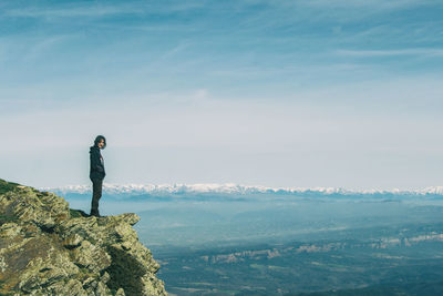 Man standing on rock against sky