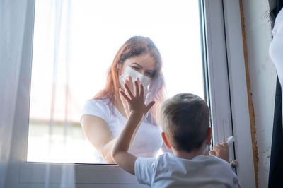 Portrait of boy sitting in glass window