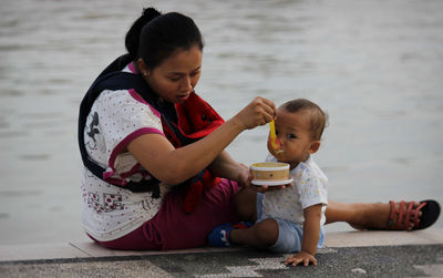 Mother feeding food to son at promenade