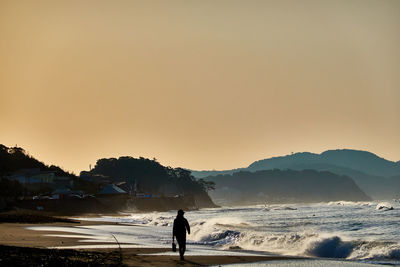 Silhouette man looking at sea against sky during sunset