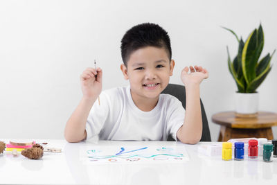 Portrait of smiling boy holding table
