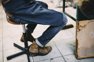 Low section of craftsperson sitting on stool in upholstery workshop