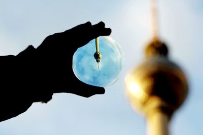 Close-up of hand holding crystal against clear sky