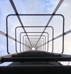 Low angle view of ladder against cloudy sky