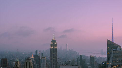 Buildings in city against sky during sunset