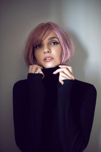 Close up portrait of a woman with pink hair and a black sweater on the background
