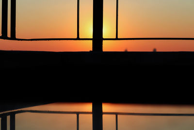 Close-up of silhouette railing against orange sky