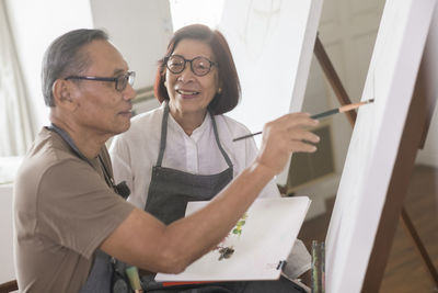 Man painting on canvas with woman at home