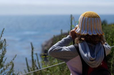 Midsection of woman standing by sea against sky