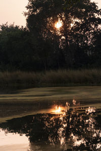 Scenic view of lake in forest against sky at sunset