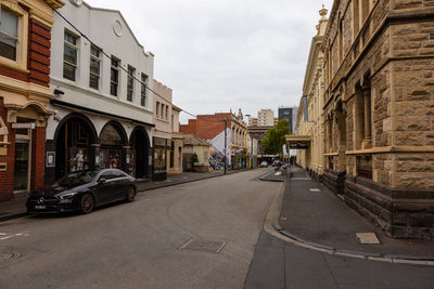 Road amidst buildings in city against sky