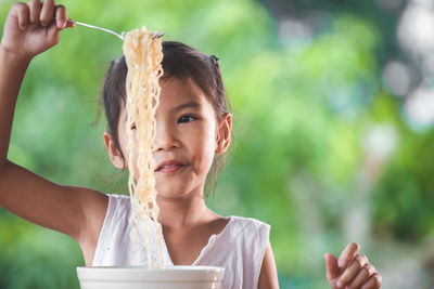 Cute girl eating noodles in public park