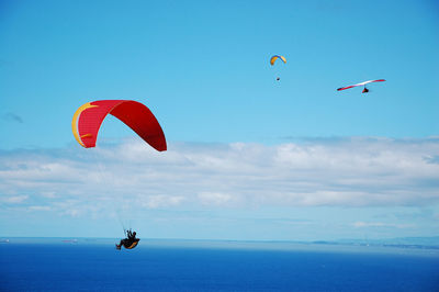 Woman paragliding over sea against sky