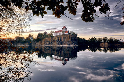 Reflection of building in lake against sky during sunset