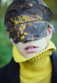 Close-up of boy with leaf on eyes