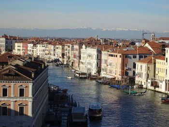 Boats in canal amidst buildings in city against sky