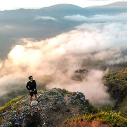 High angle view of young man standing on mountain during sunset