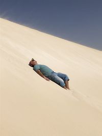 Side view of man on sand at desert against sky