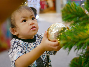 Cute baby girl standing by christmas tree at home