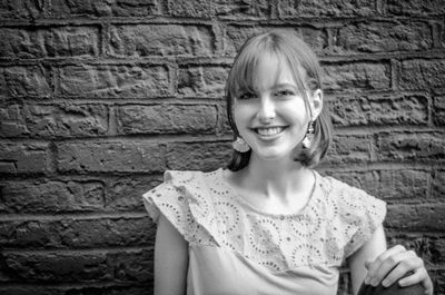 Portrait of smiling young woman against wall