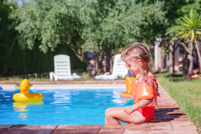 Side view of young woman sitting in swimming pool