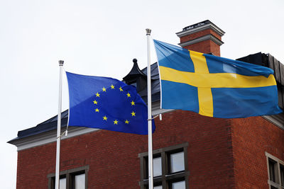 Low angle view of flag against building against clear sky