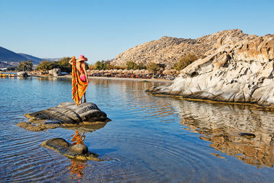 Man standing on rock against sky