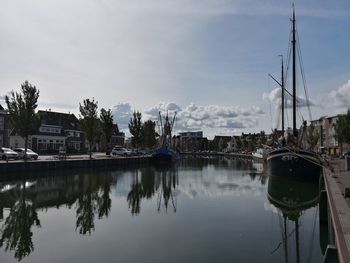 Sailboats moored in lake against sky in city