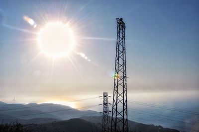 Low angle view of silhouette electricity pylon against sky