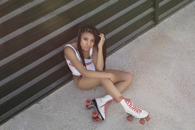 Young slim woman sitting in elegant swimsuit and roller skates