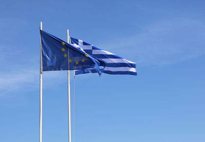 Low angle view of flags against blue sky