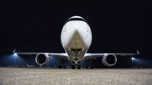 Low angle view of illuminated airplane flying in sky at night