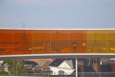 Reflection of building on glass window against sky