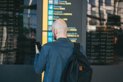 Rear view of man using mobile phone in city