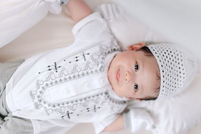 High angle portrait of baby boy lying down on bed