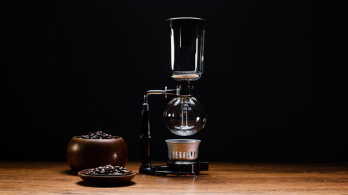 Close-up of wineglass on table against black background