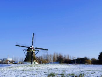 Traditional windmill on field against clear sky